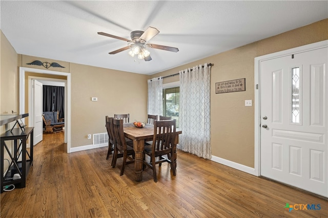 dining room featuring hardwood / wood-style floors, ceiling fan, and a textured ceiling