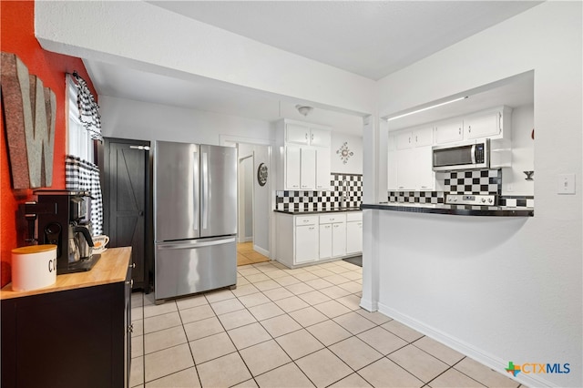 kitchen with white cabinetry, stainless steel appliances, light tile patterned floors, and tasteful backsplash