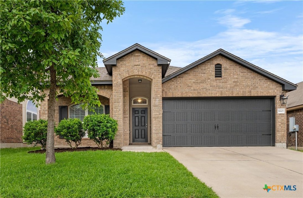 traditional home featuring brick siding, an attached garage, driveway, and a front yard