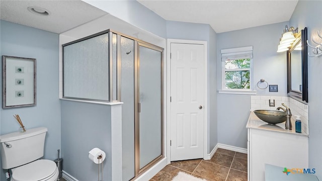 bathroom with vanity, a shower with door, backsplash, tile patterned floors, and toilet