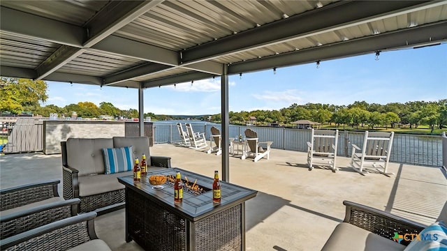 view of patio featuring a water view and an outdoor living space with a fire pit