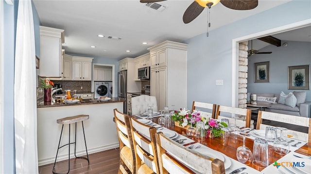 dining area featuring sink, dark hardwood / wood-style flooring, lofted ceiling with beams, and washer / dryer