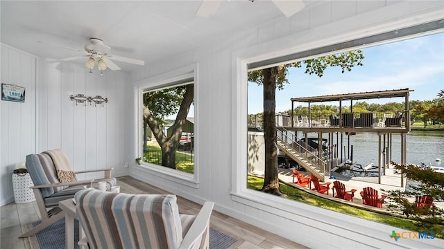 sunroom featuring a water view and ceiling fan