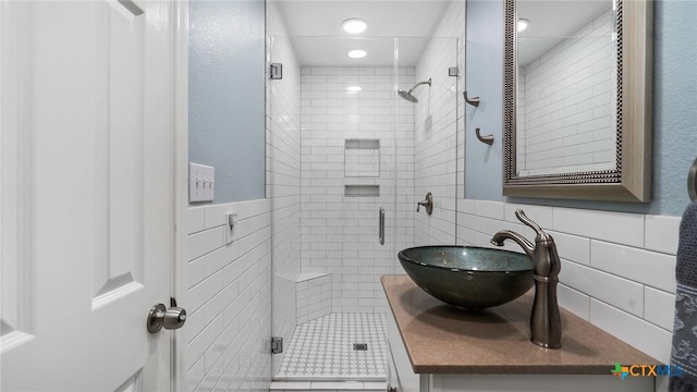 bathroom with vanity, a shower with door, and tile walls