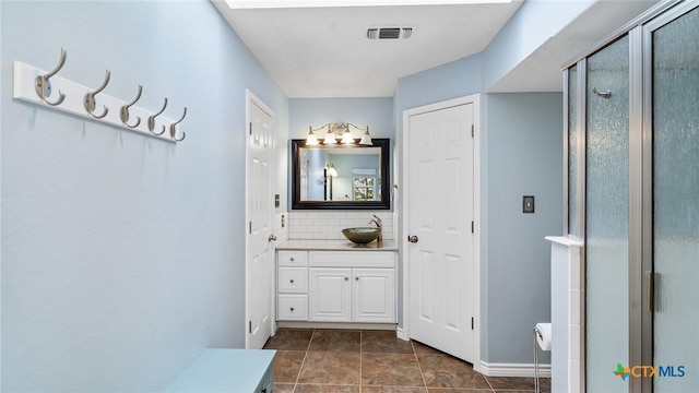 bathroom featuring tasteful backsplash, tile patterned floors, vanity, and a shower with shower door