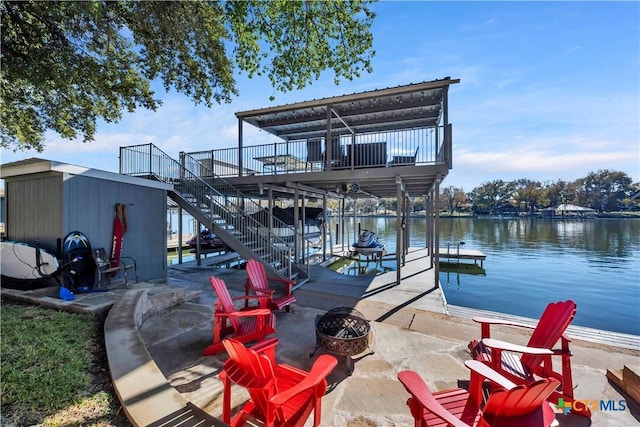 dock area featuring a fire pit, a deck with water view, and a patio