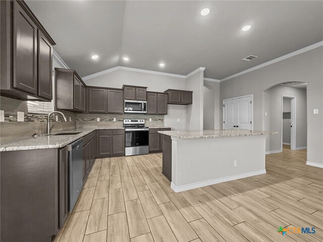 5205 Colina Dr, Killeen, TX 76549 - kitchen featuring stainless steel appliances, a sink, arched walkways, dark brown cabinetry, and crown molding