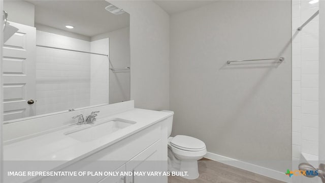 bathroom featuring toilet, hardwood / wood-style floors, vanity, and a tile shower