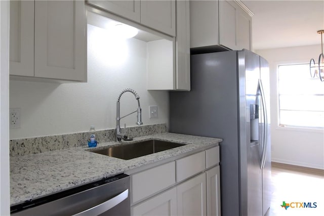 kitchen featuring a sink, light stone countertops, white cabinetry, and stainless steel appliances