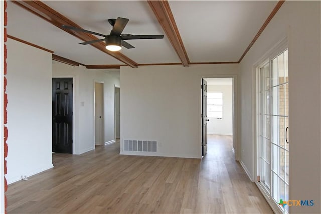 spare room featuring beam ceiling, light wood-style floors, and visible vents