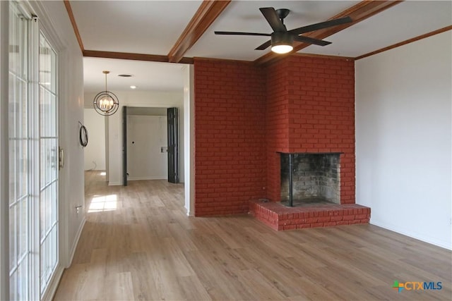 unfurnished living room featuring a healthy amount of sunlight, wood finished floors, a fireplace, and ornamental molding