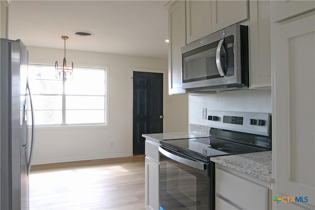 kitchen featuring light stone counters, baseboards, light wood finished floors, stainless steel appliances, and decorative light fixtures