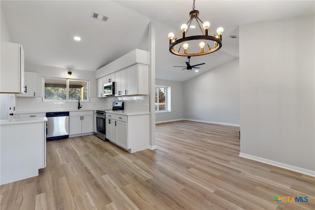 kitchen with white cabinets, pendant lighting, appliances with stainless steel finishes, and vaulted ceiling