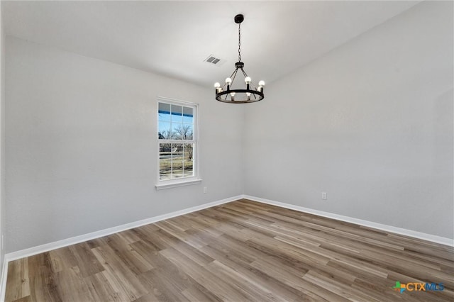 unfurnished room with hardwood / wood-style flooring and a chandelier