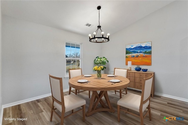 dining area featuring an inviting chandelier, lofted ceiling, and hardwood / wood-style flooring