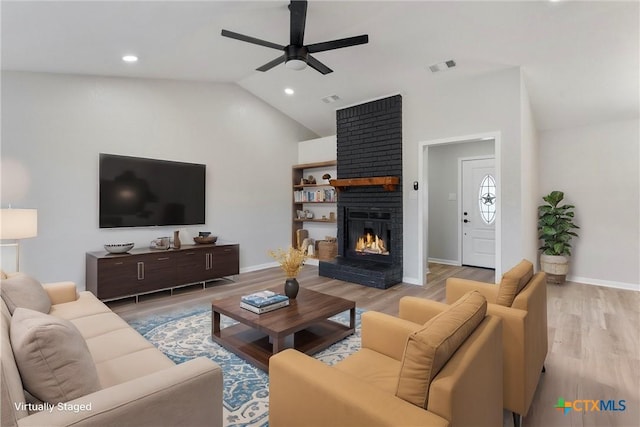 living room featuring light wood-type flooring, ceiling fan, lofted ceiling, and a fireplace