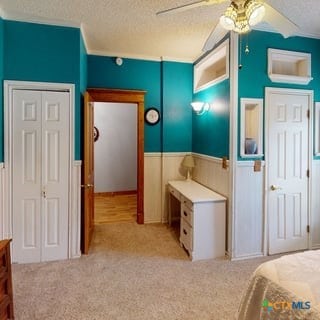 501 Live Oak St, Gatesville, TX 76528 - bedroom featuring a textured ceiling, a wainscoted wall, light colored carpet, and ceiling fan