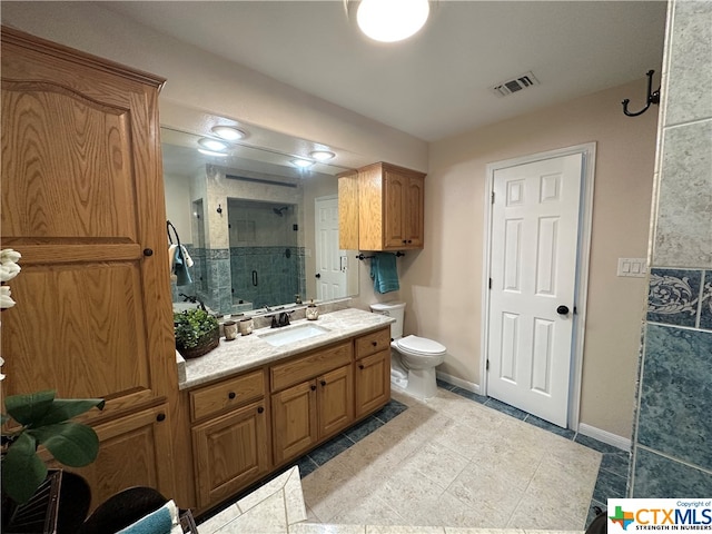 bathroom with tile patterned floors, vanity, toilet, and a shower with shower door