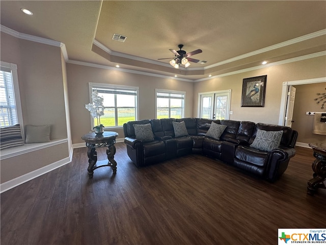 living room featuring ceiling fan, ornamental molding, dark wood-type flooring, and a tray ceiling