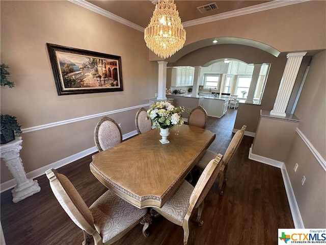 dining room with decorative columns, crown molding, dark wood-type flooring, and a notable chandelier