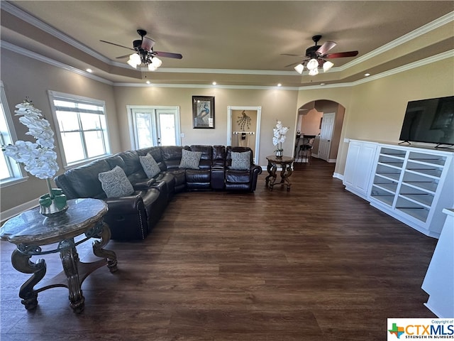 living room with dark hardwood / wood-style floors, ceiling fan, ornamental molding, and a tray ceiling