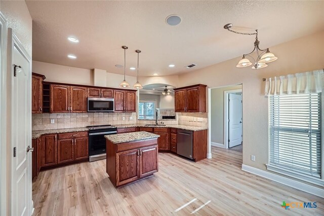 240 Hummingbird Way, Martindale, TX 78655 - kitchen featuring appliances with stainless steel finishes, a sink, a center island, tasteful backsplash, and light wood-style flooring