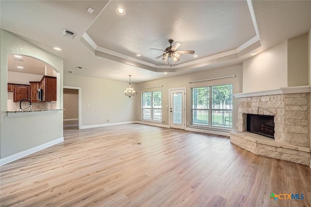240 Hummingbird Way, Martindale, TX 78655 - unfurnished living room with a raised ceiling, a ceiling fan, a fireplace, light wood-style floors, and crown molding