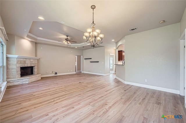 240 Hummingbird Way, Martindale, TX 78655 - unfurnished living room featuring a chandelier, ceiling fan, light wood-style floors, a fireplace, and a tray ceiling