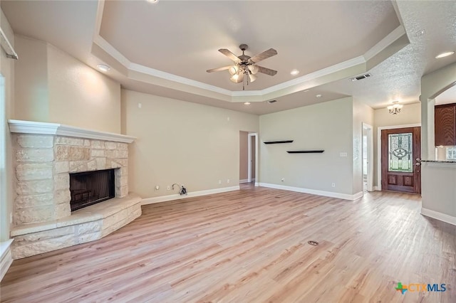 240 Hummingbird Way, Martindale, TX 78655 - unfurnished living room featuring a raised ceiling, crown molding, a ceiling fan, a fireplace, and light wood-type flooring