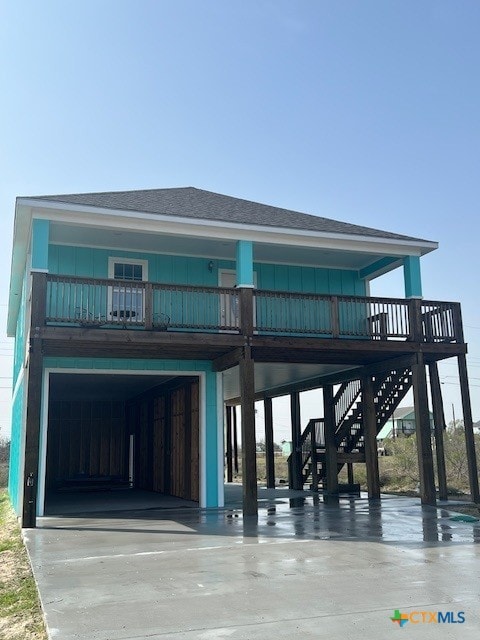 view of front facade with a carport, driveway, stairway, and board and batten siding