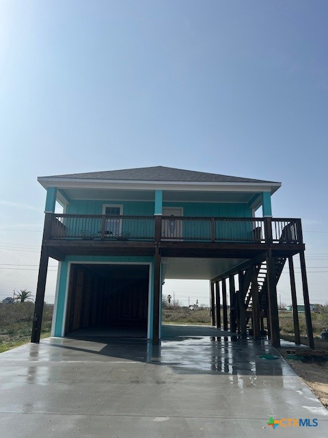 coastal home featuring a carport, a garage, stairs, and concrete driveway