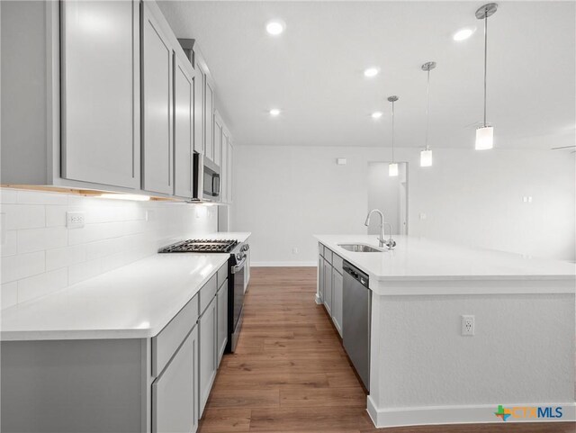 1513 Passmore Downs, New Braunfels, TX 78130 - kitchen featuring appliances with stainless steel finishes, a sink, light wood-style flooring, backsplash, and light countertops