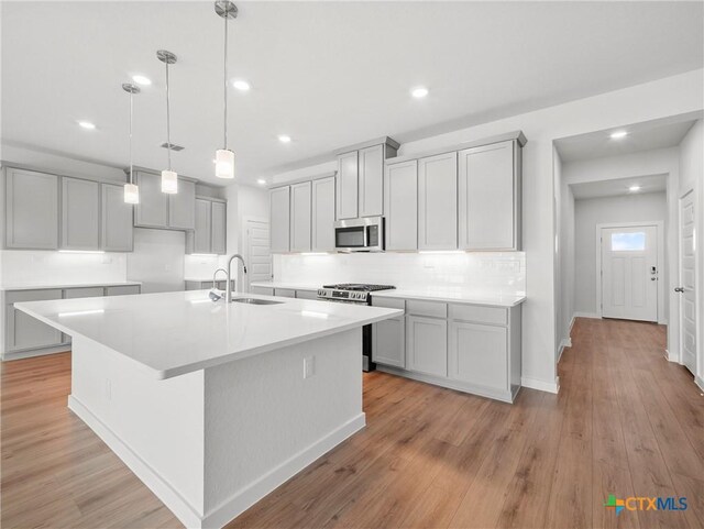 1513 Passmore Downs, New Braunfels, TX 78130 - kitchen with appliances with stainless steel finishes, a sink, decorative backsplash, an island with sink, and recessed lighting