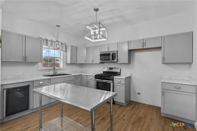 905 N Navarro St, Victoria, TX 77901 - kitchen featuring appliances with stainless steel finishes, gray cabinets, a chandelier, beverage cooler, and dark wood-type flooring