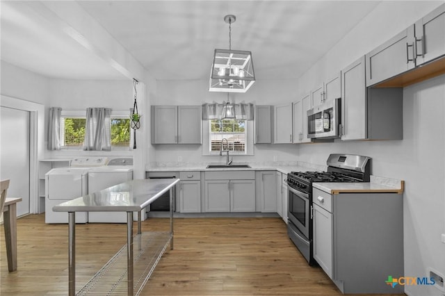 905 N Navarro St, Victoria, TX 77901 - kitchen featuring separate washer and dryer, stainless steel appliances, gray cabinets, and a chandelier