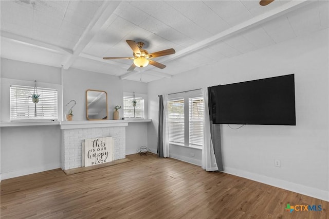 905 N Navarro St, Victoria, TX 77901 - unfurnished living room featuring beamed ceiling, wood finished floors, a ceiling fan, and a fireplace