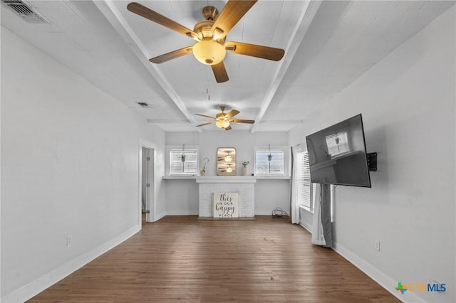 905 N Navarro St, Victoria, TX 77901 - unfurnished living room featuring beamed ceiling, wood finished floors, a ceiling fan, and a fireplace