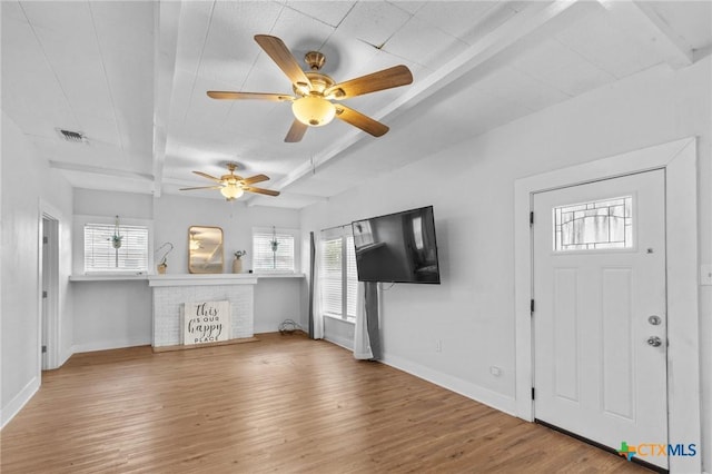 905 N Navarro St, Victoria, TX 77901 - unfurnished living room with beamed ceiling, wood finished floors, a ceiling fan, and a brick fireplace