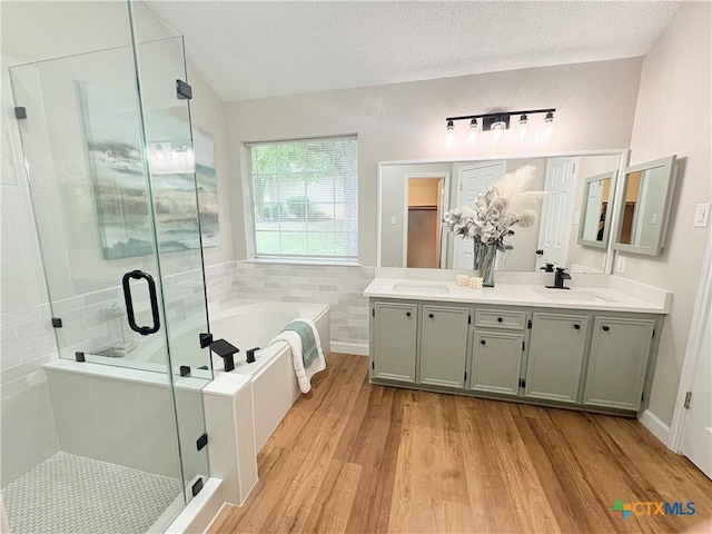 421 Arapaho Dr, Harker Heights, TX 76548 - full bath featuring wood finished floors, a bath, a shower stall, double vanity, and a textured ceiling