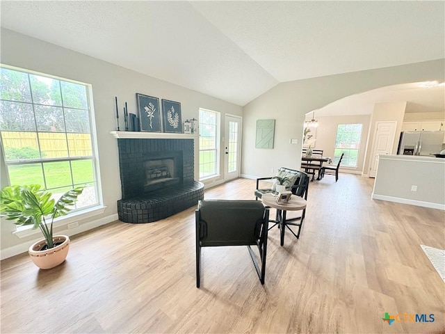 421 Arapaho Dr, Harker Heights, TX 76548 - living area with light wood-type flooring, baseboards, a brick fireplace, lofted ceiling, and arched walkways