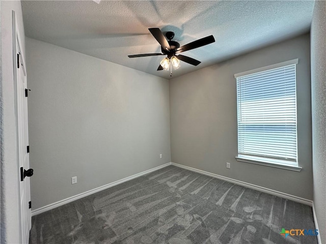 unfurnished room featuring ceiling fan, dark colored carpet, baseboards, and a textured ceiling