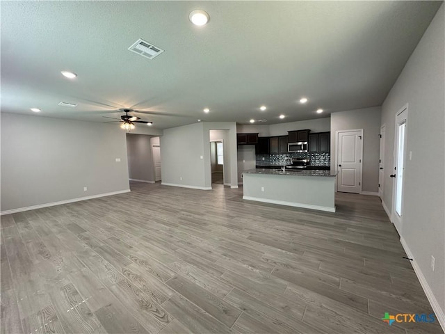 unfurnished living room with baseboards, a sink, a ceiling fan, recessed lighting, and light wood-type flooring