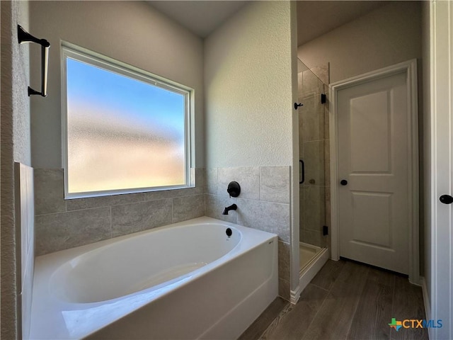 full bathroom featuring wood finished floors, a stall shower, and a bath