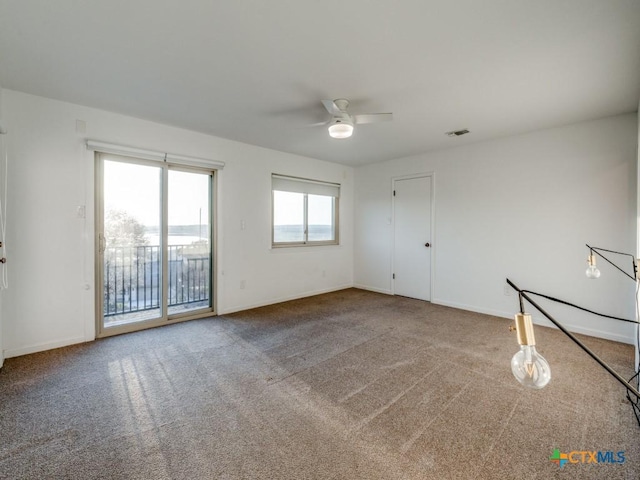 empty room with carpet floors, baseboards, and visible vents