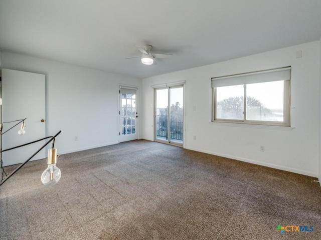 carpeted spare room featuring ceiling fan and baseboards