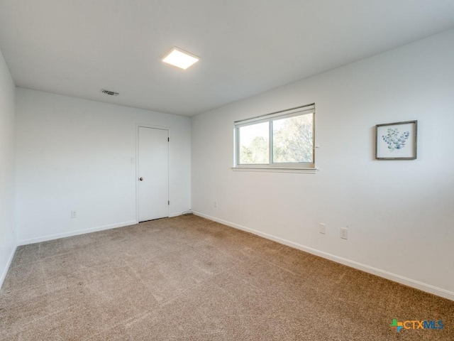 carpeted spare room featuring baseboards and visible vents