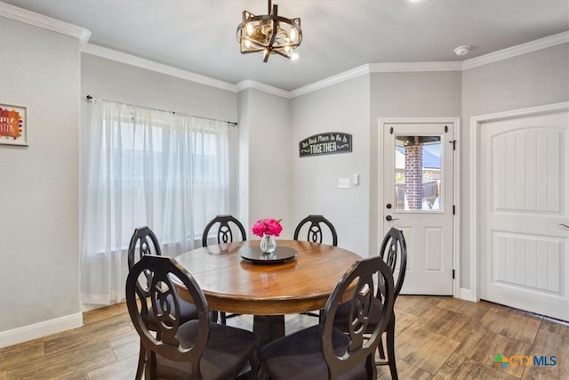 dining room featuring light wood-style floors, a notable chandelier, crown molding, and baseboards