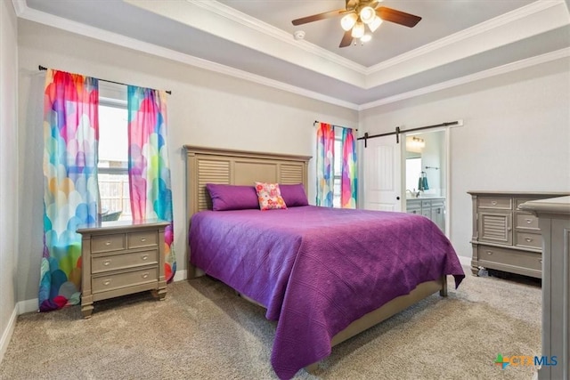 bedroom featuring carpet floors, a tray ceiling, a barn door, ornamental molding, and baseboards