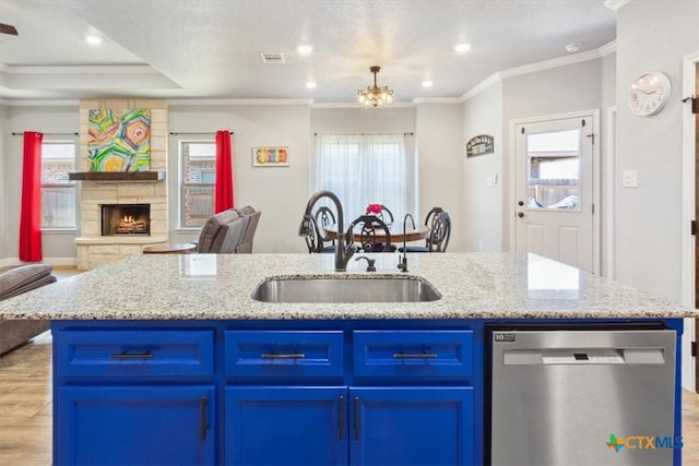 kitchen featuring open floor plan, a sink, dishwasher, and blue cabinetry