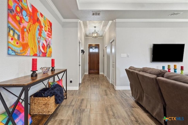 foyer entrance featuring visible vents, crown molding, baseboards, and wood finished floors